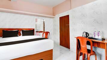 Una habitación de hotel con una cama, un escritorio, una silla, un espejo y un armario.