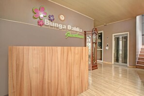 A reception desk area with a wooden counter, a wall-mounted clock, and a sign that reads 'Bunga Dahlia Guesthouse.' - Luxury Deluxe DBL Retreat W/ Free Wifi and Parking (Jakarta)
