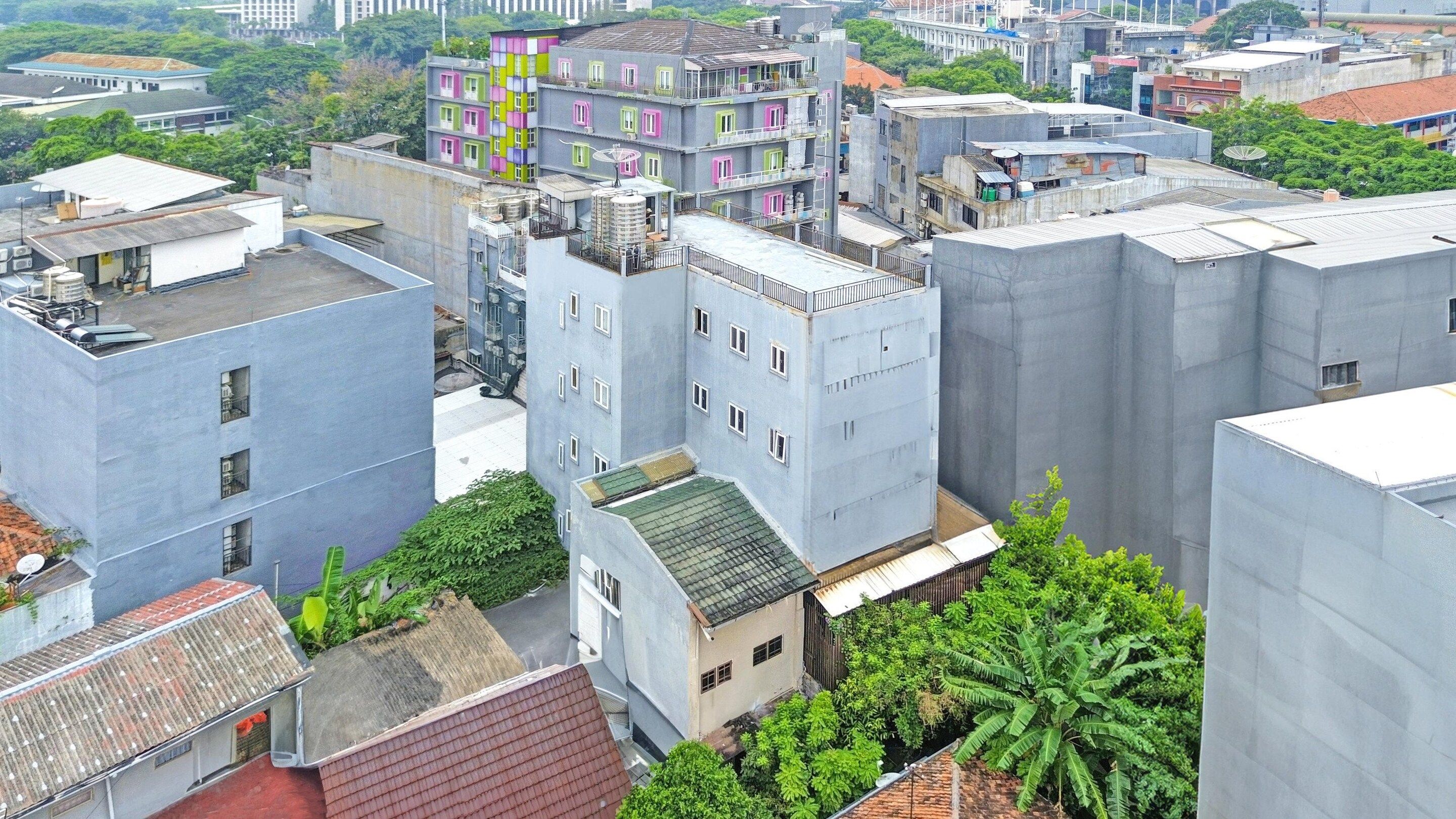 A multi-story building with a flat roof, surrounded by other buildings and greenery.