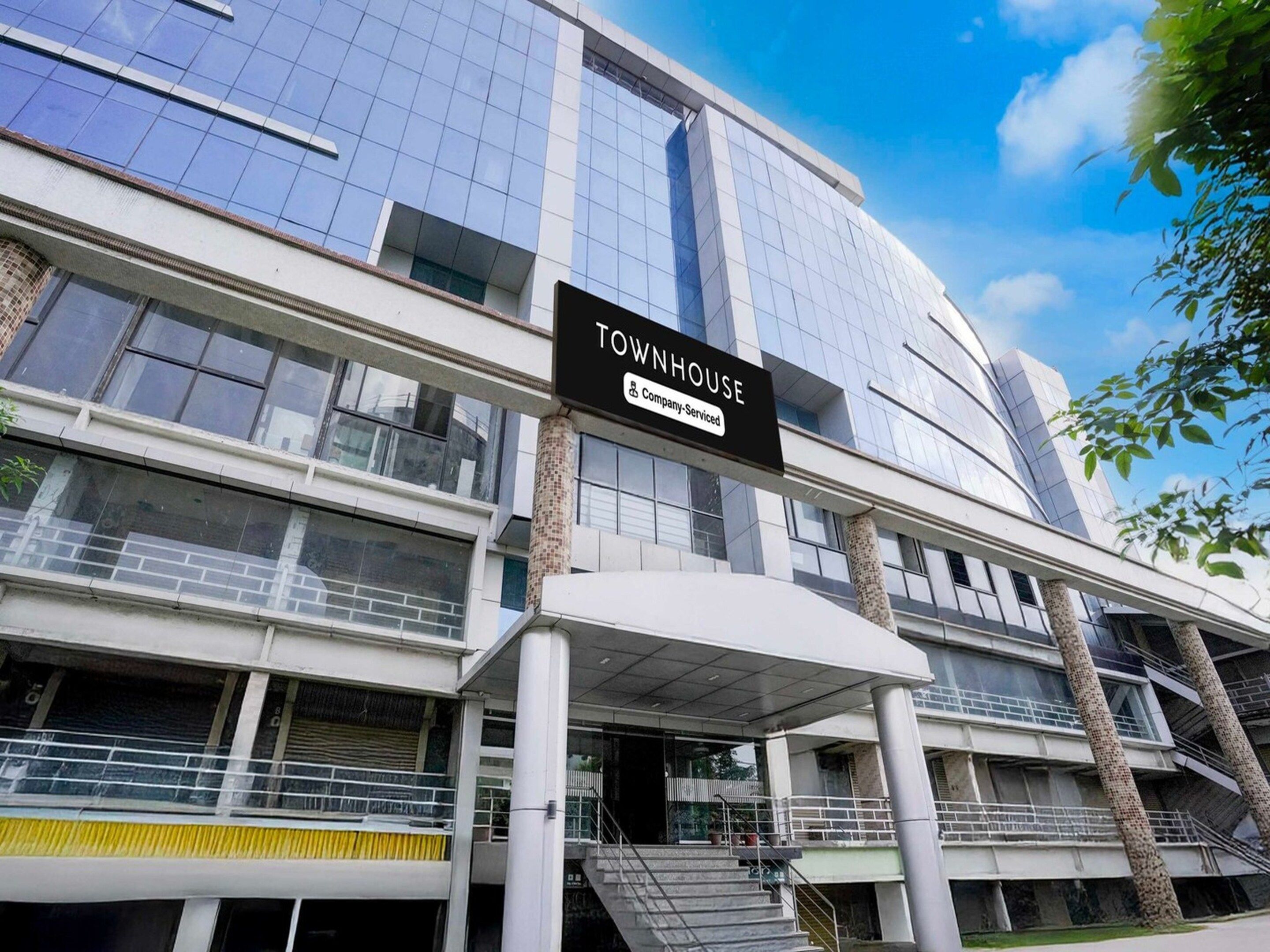 A modern building with a sign reading 'TOWNHOUSE 5 Company-Serviced.'