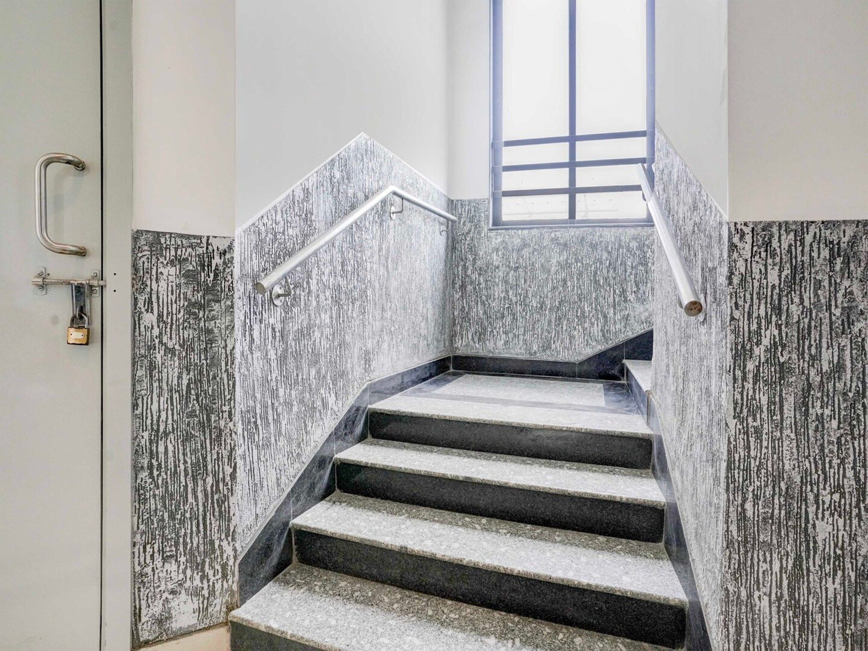 A staircase with a metal handrail and a window at the top.