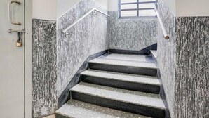 Un escalier avec une rampe métallique et une fenêtre en haut.