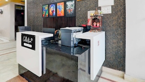 A reception desk with a clock, framed artwork, and a small shrine. - Collection O Insaf Nagar Munshipuliya  (Lucknow)