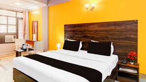 A hotel room with a large bed, a desk with a chair, a bedside table with a lamp, and a window with curtains. - Collection O Insaf Nagar Munshipuliya  (Lucknow)