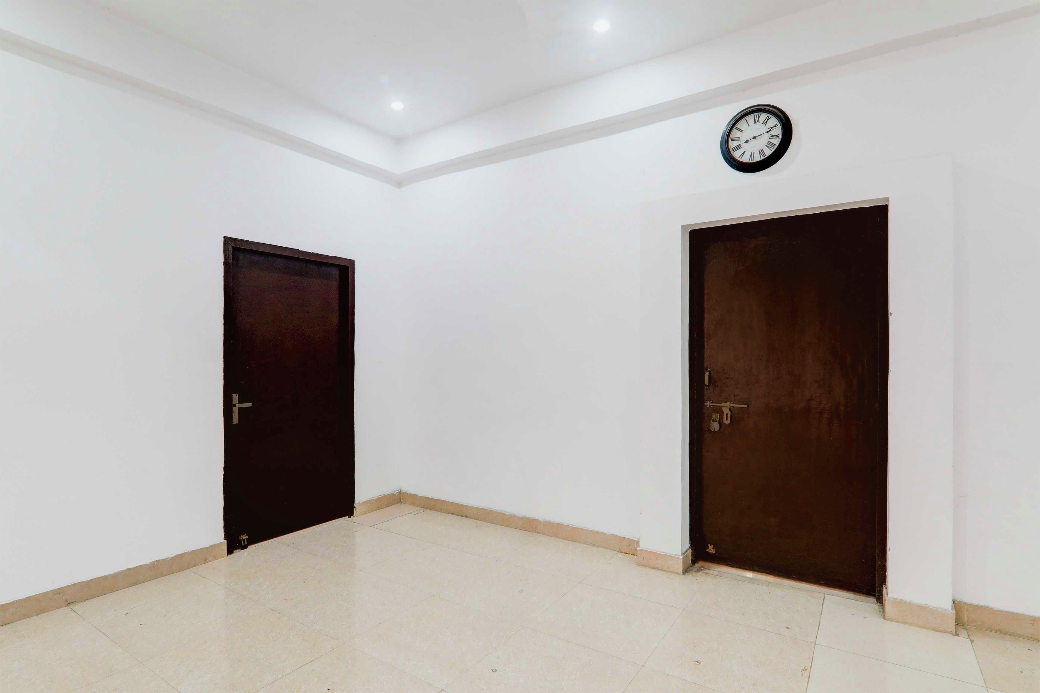 A room with two dark wooden doors, white walls, and a tiled floor.