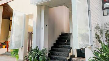 Un escalier menant à l’entrée d’un bâtiment à la façade blanche et doté d’une rampe métallique.