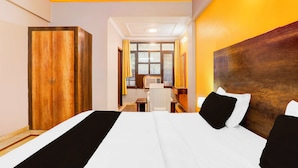 A hotel room with a large bed, a wooden wardrobe, a desk, and a view through a window. - Collection O Insaf Nagar Munshipuliya  (Lucknow)
