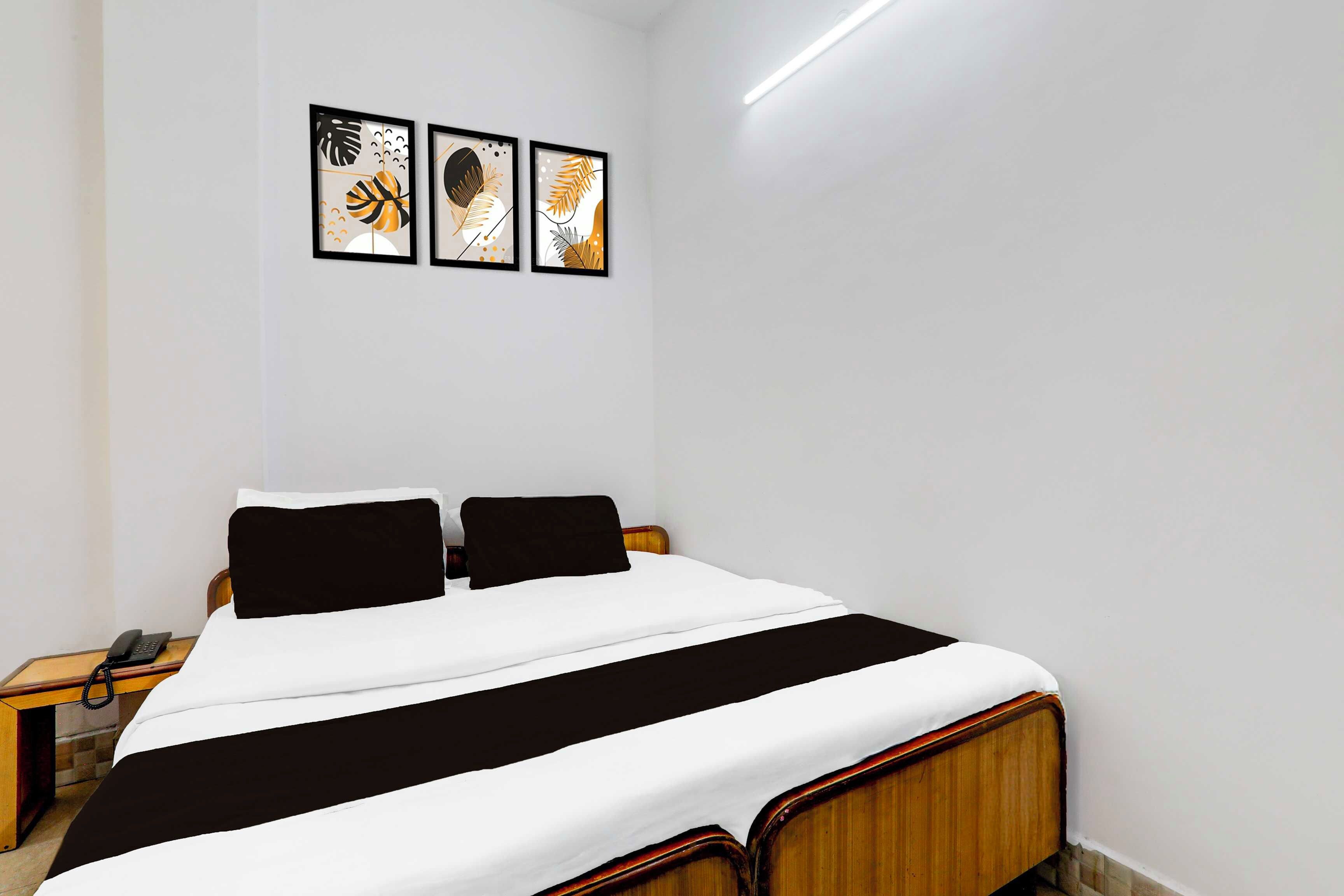 A bedroom with a bed, two nightstands, and three framed artworks on the wall.