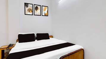 A bedroom with a bed, two nightstands, and three framed artworks on the wall.