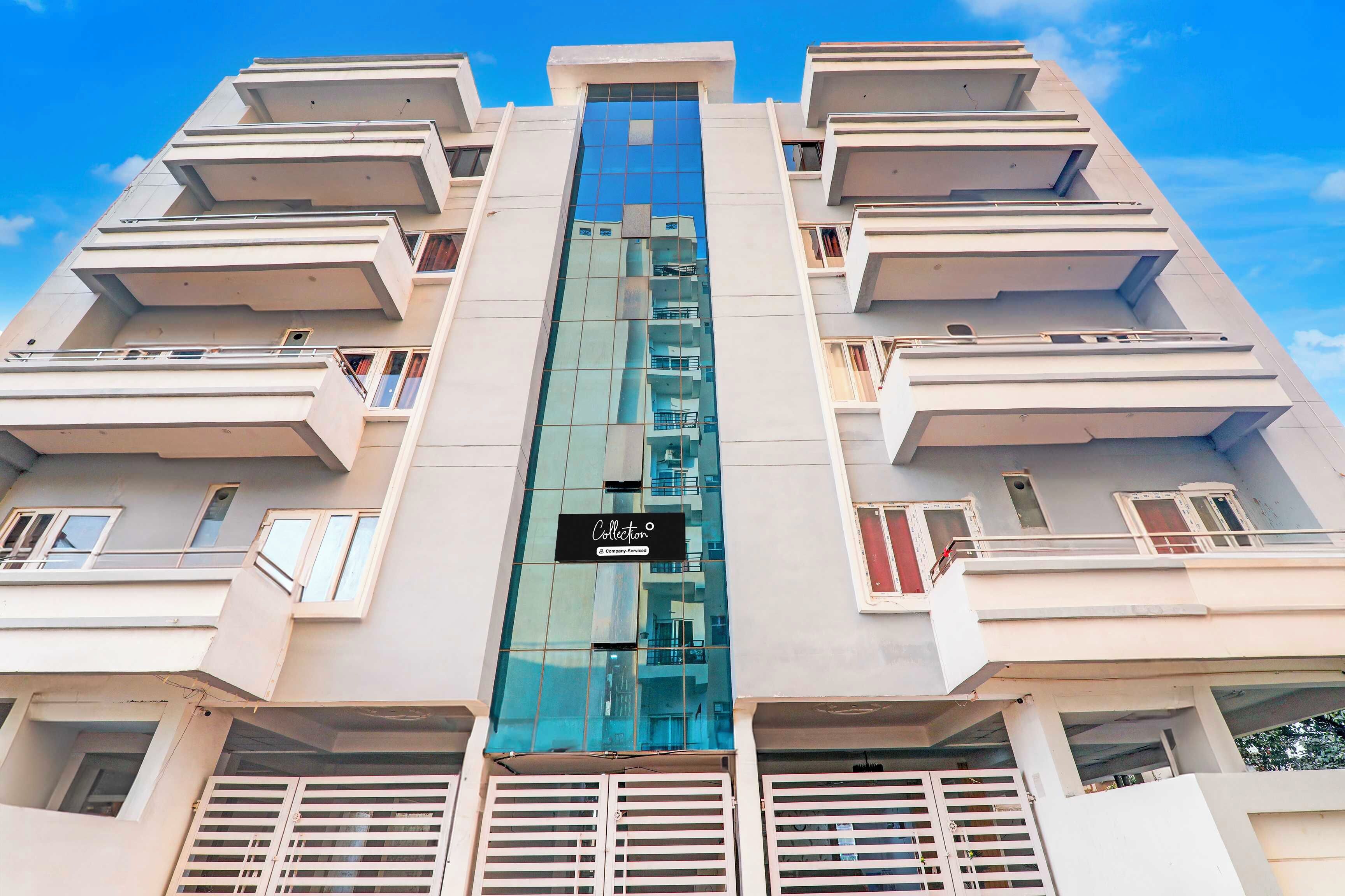 A multi-story building with balconies and a central glass elevator shaft.