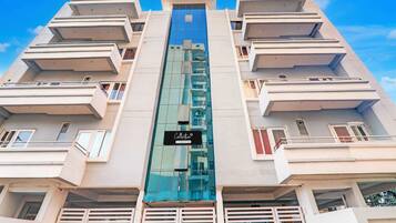 A multi-story building with balconies and a central glass elevator shaft.