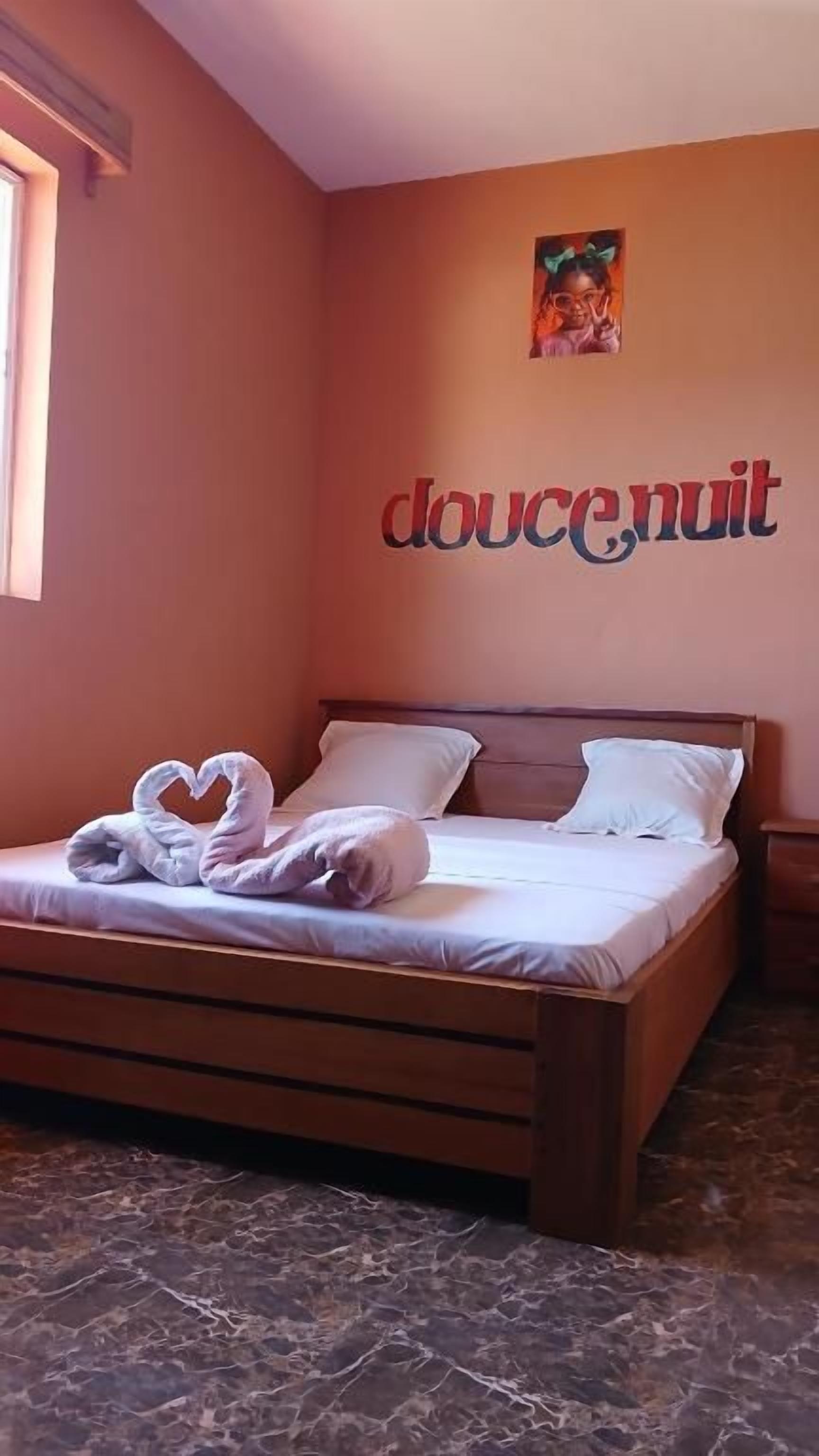 Un dormitorio con cama, almohadas y una pared con la palabra 'doucenuit'.