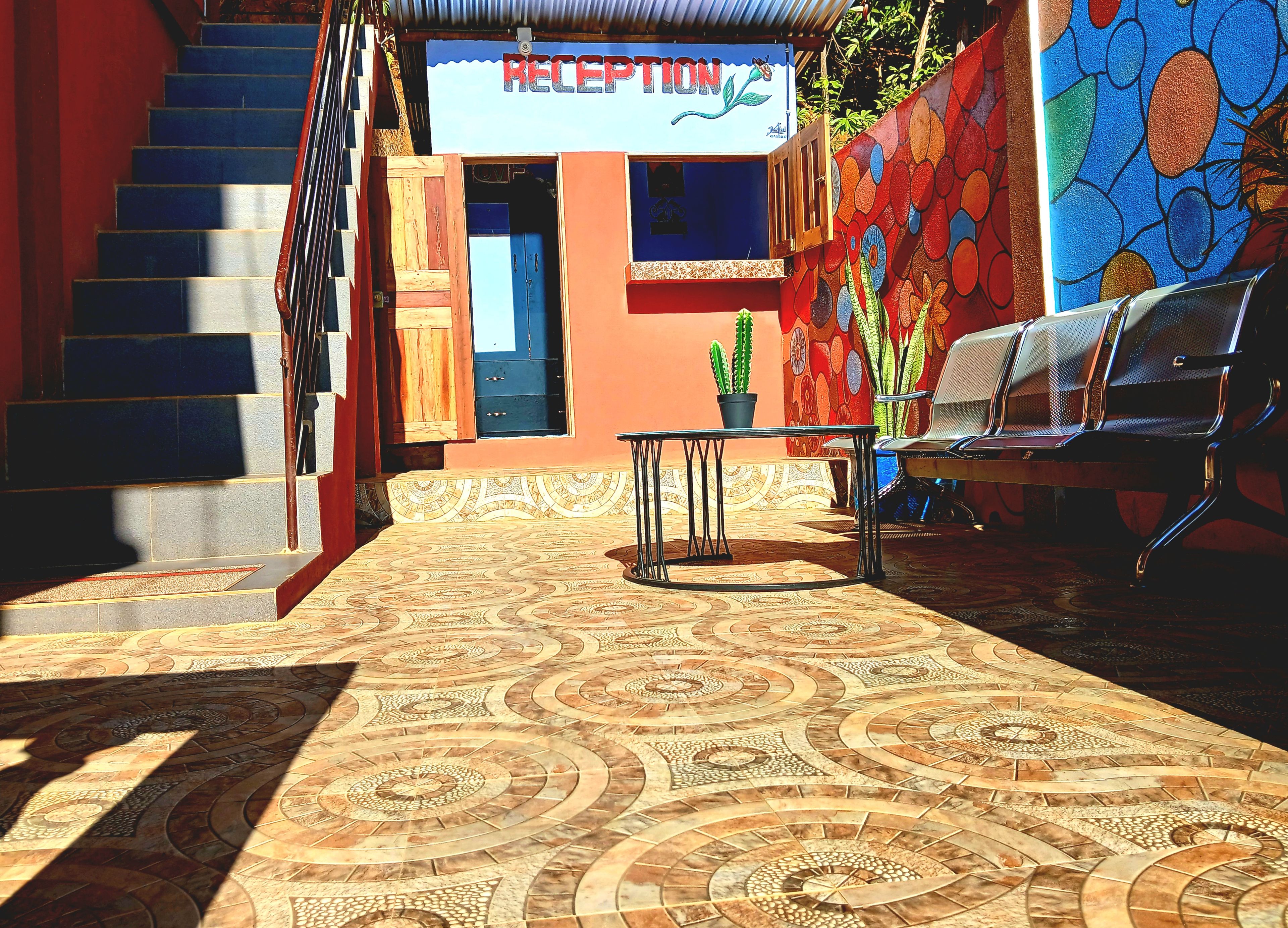 Zona de recepción con una escalera, mostrador de recepción y un área de estar con sillas.