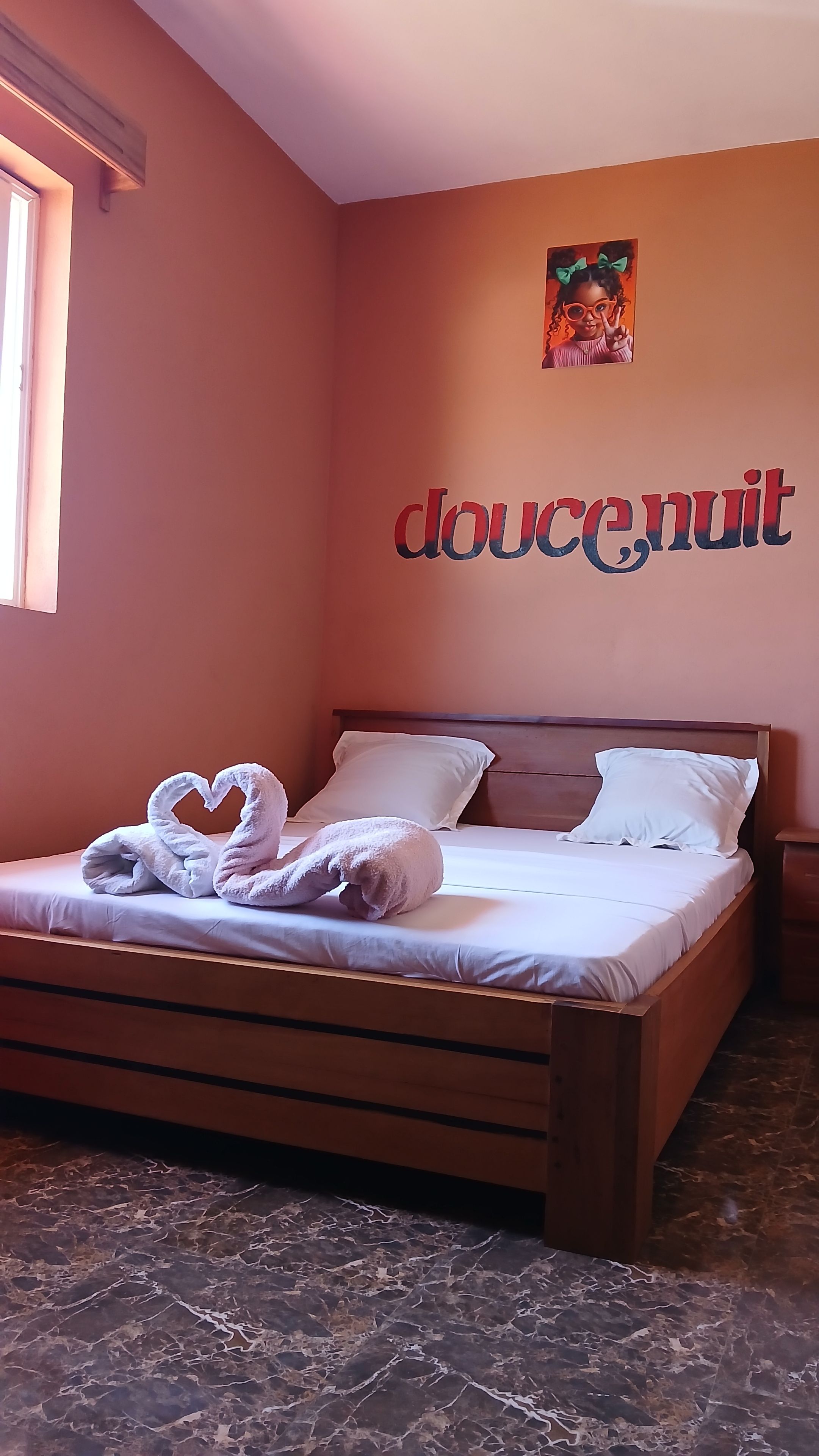 Une chambre à coucher avec un lit, des oreillers et un mur sur lequel est écrit le mot « doucenuit ».