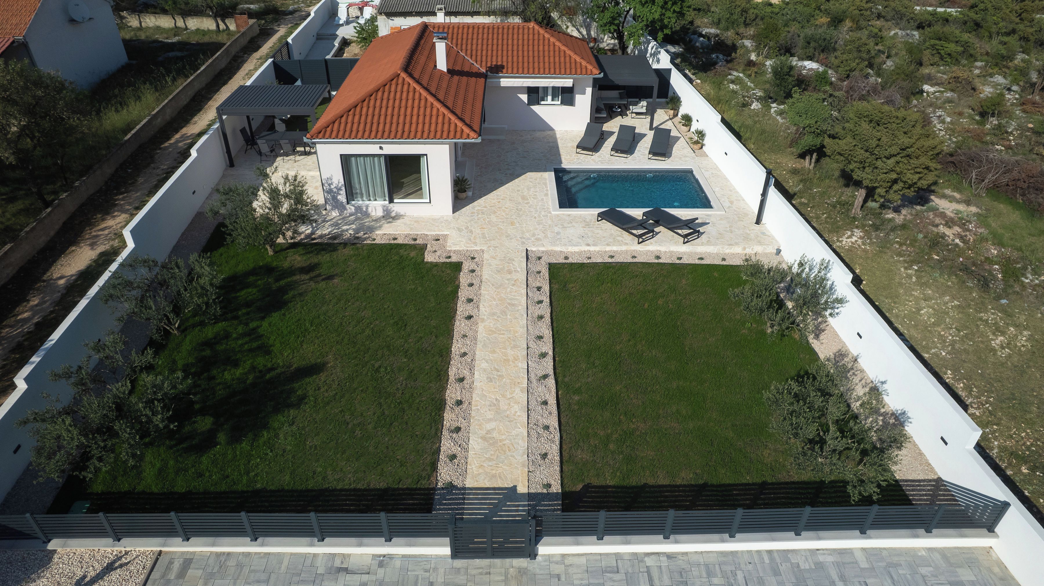 A modern house with a swimming pool, a covered patio, and a well-maintained lawn.