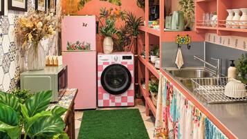 Een kleine keuken met een wasmachine, een spoelbak en diverse planten.