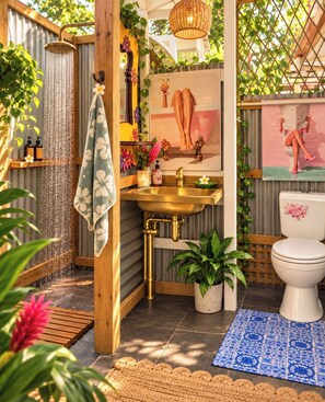 A bathroom with a shower, sink, toilet, and decorative elements like plants and artwork.