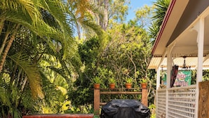A patio area with a bench, a covered grill, and a white fence with decorative elements.