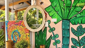 A room with a blue table, a mirror, and a wall mural featuring a large plant and a colorful octopus design.