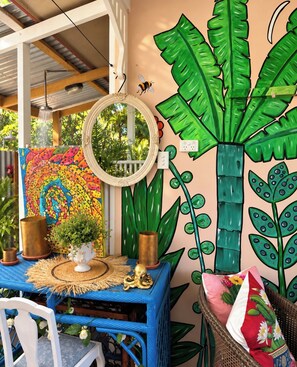 A room with a blue table, a mirror, and a wall mural featuring a large plant and a colorful octopus design.