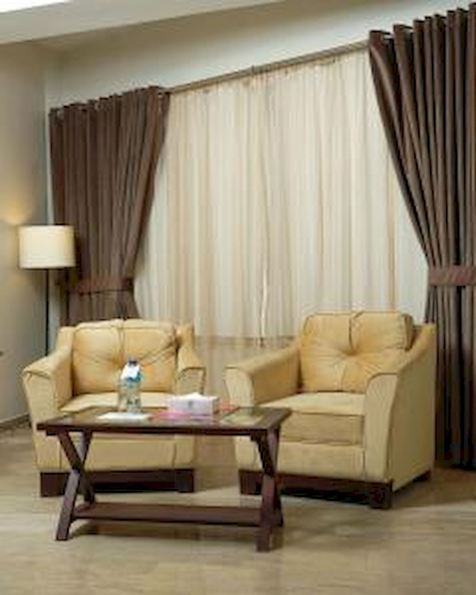 A living room with two beige sofas, a wooden coffee table, and a lamp on a side table.