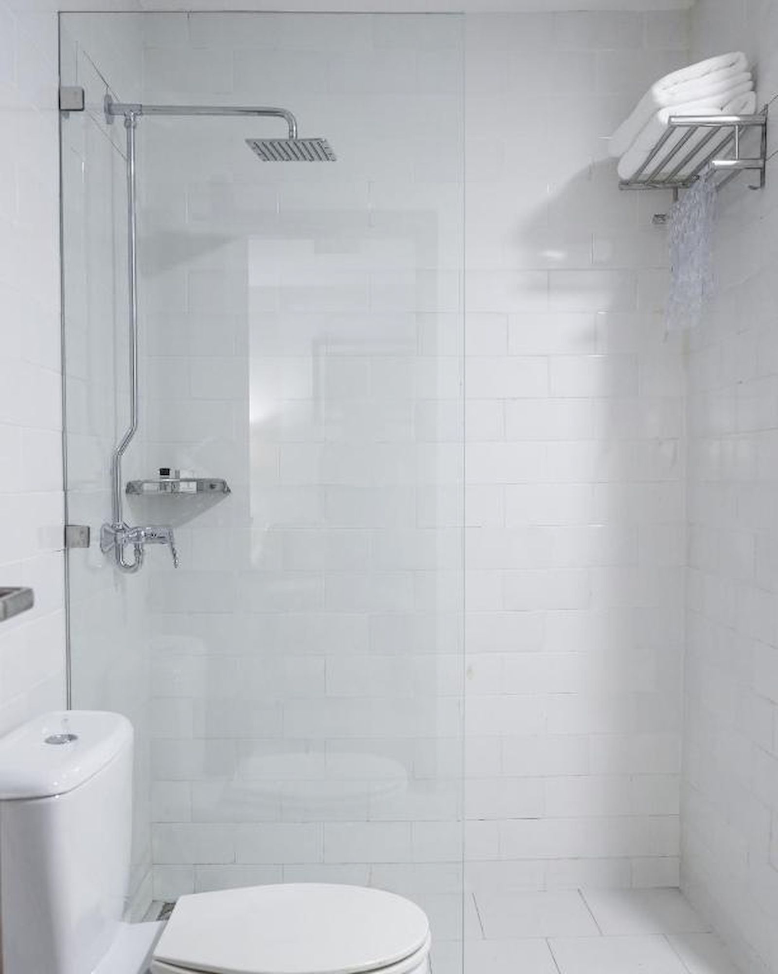 Un baño moderno con ducha acristalada, inodoro blanco y barra para toallas.