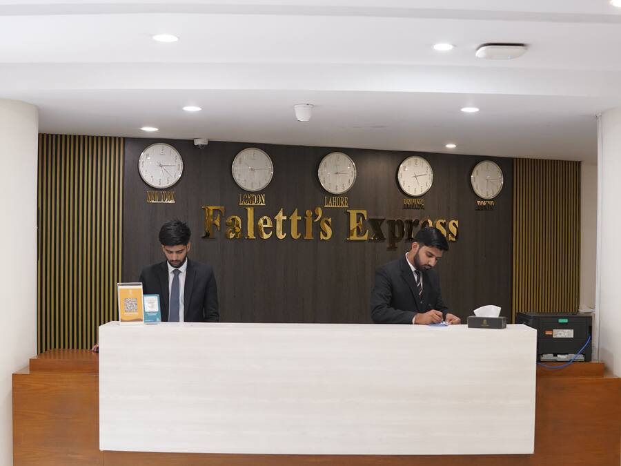 Eine Hotelrezeption mit Uhren, die verschiedene Großstadtdaten anzeigen, einem Schild mit der Aufschrift 'The Falett's Express' und einem modernen Innenraum.