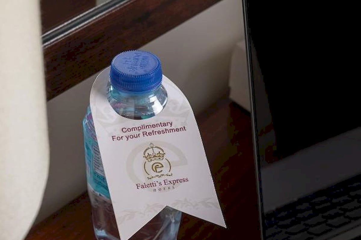 A water bottle with a label on a wooden surface next to a laptop.