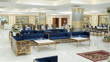 A spacious lobby with a seating area, tables, and decorative elements.