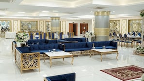 A spacious lobby with a seating area, tables, and decorative elements.