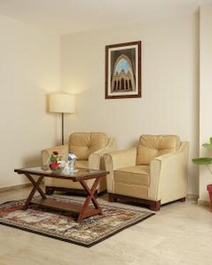 A living room with two beige armchairs, a coffee table, a floor lamp, and a framed picture on the wall. - Faletti's Express- Shimla Hill (Lahore)