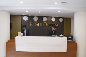 A reception desk with two staff members, a clock wall, and a sign reading 'Faletti's Express'.
