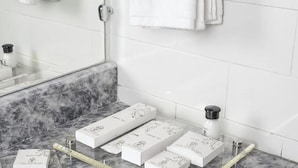 A bathroom with a marble countertop, a glass shower enclosure, and a towel rack with folded towels.