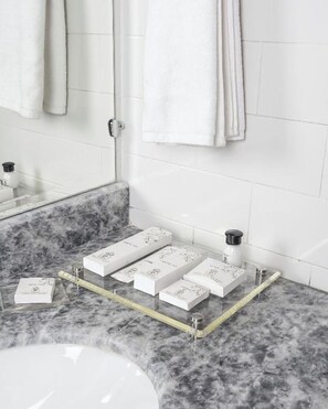 Un baño con encimera de mármol, cabina de ducha de vidrio y toallero con toallas dobladas.