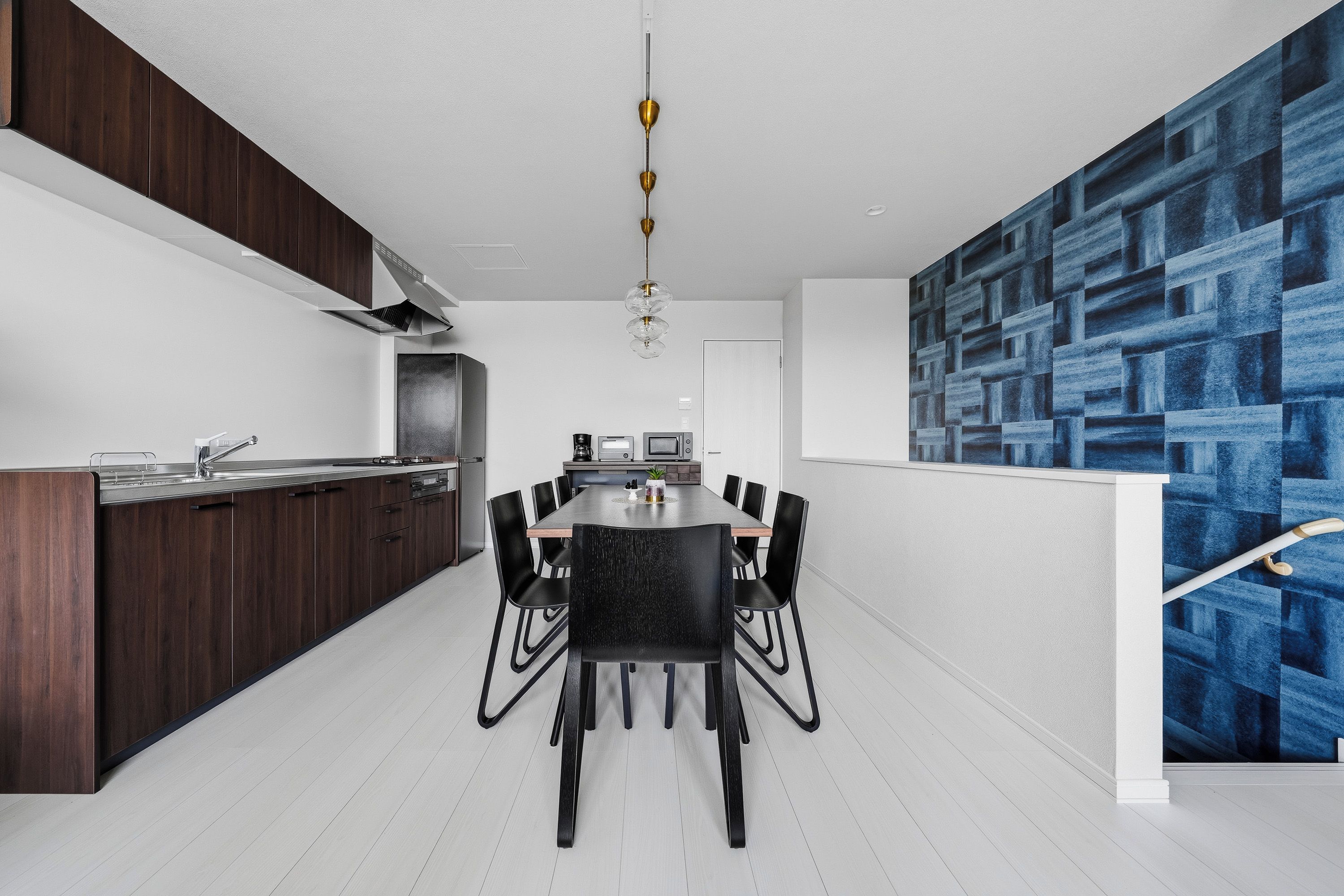 A modern kitchen with dark wood cabinets, a stainless steel countertop, and a dining area with a black table and chairs.