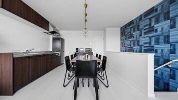 A modern kitchen with dark wood cabinets, a stainless steel countertop, and a dining area with a black table and chairs.