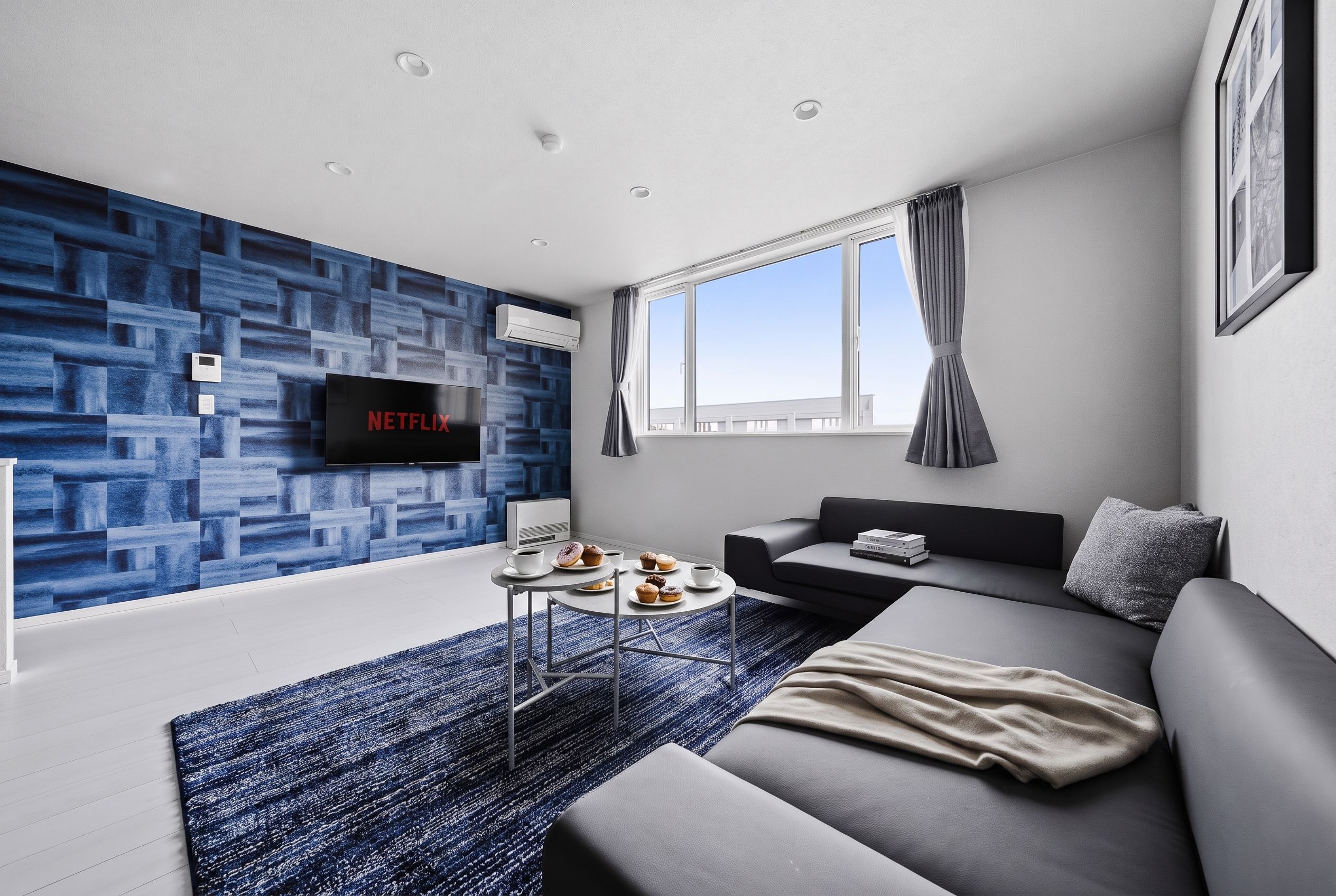 A modern living room with a flat-screen TV, a sofa, a coffee table, and a patterned wall.
