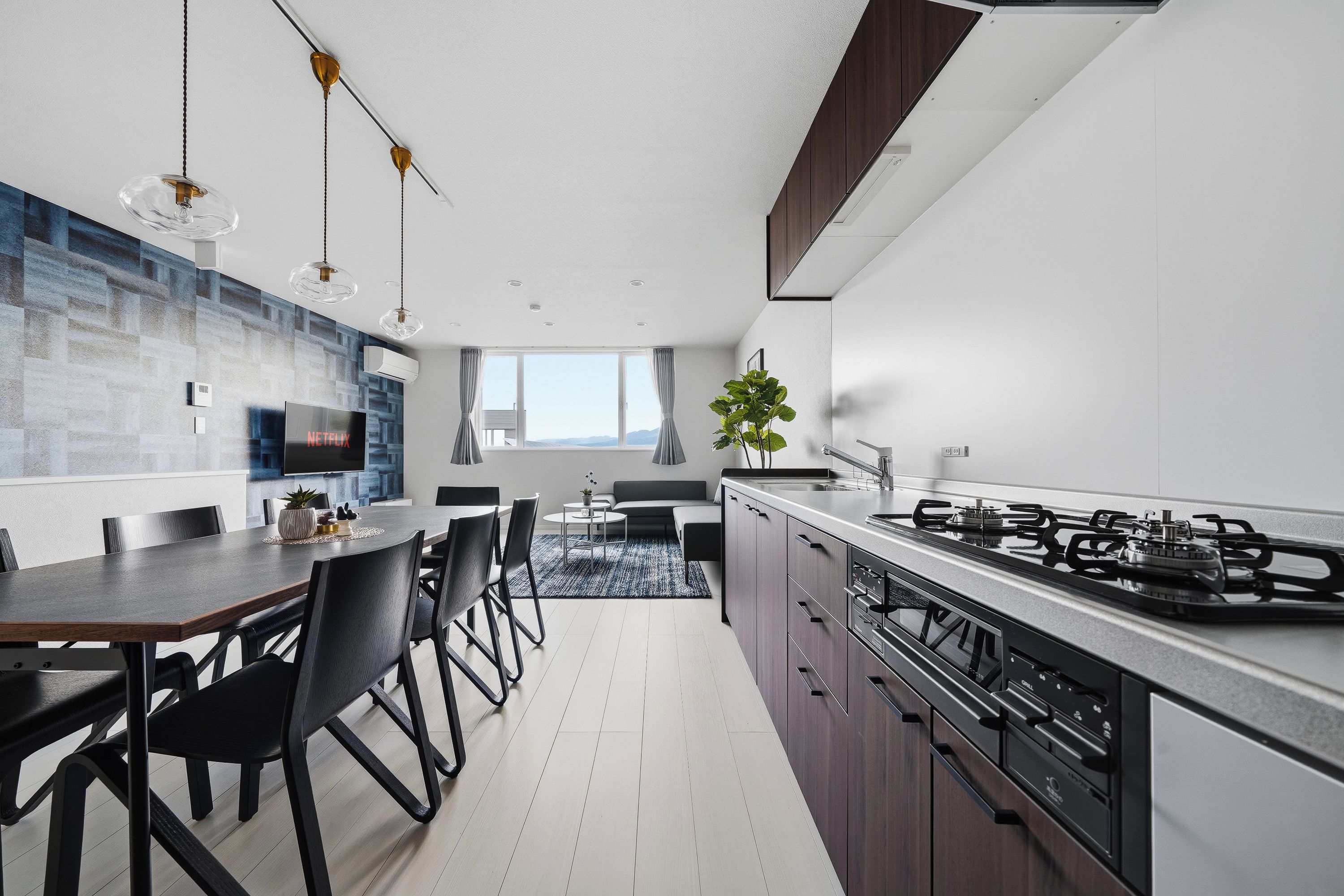A modern kitchen with a dining area, a large window, and a view of the outdoors.