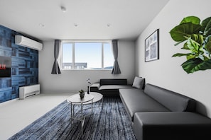 A modern living room with a sofa, a coffee table, and a large window. - Snow (Furano)