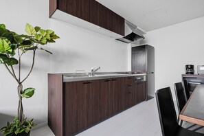 A modern kitchen with dark wood cabinets, a stainless steel sink, and a built-in oven. - Snow (Furano)