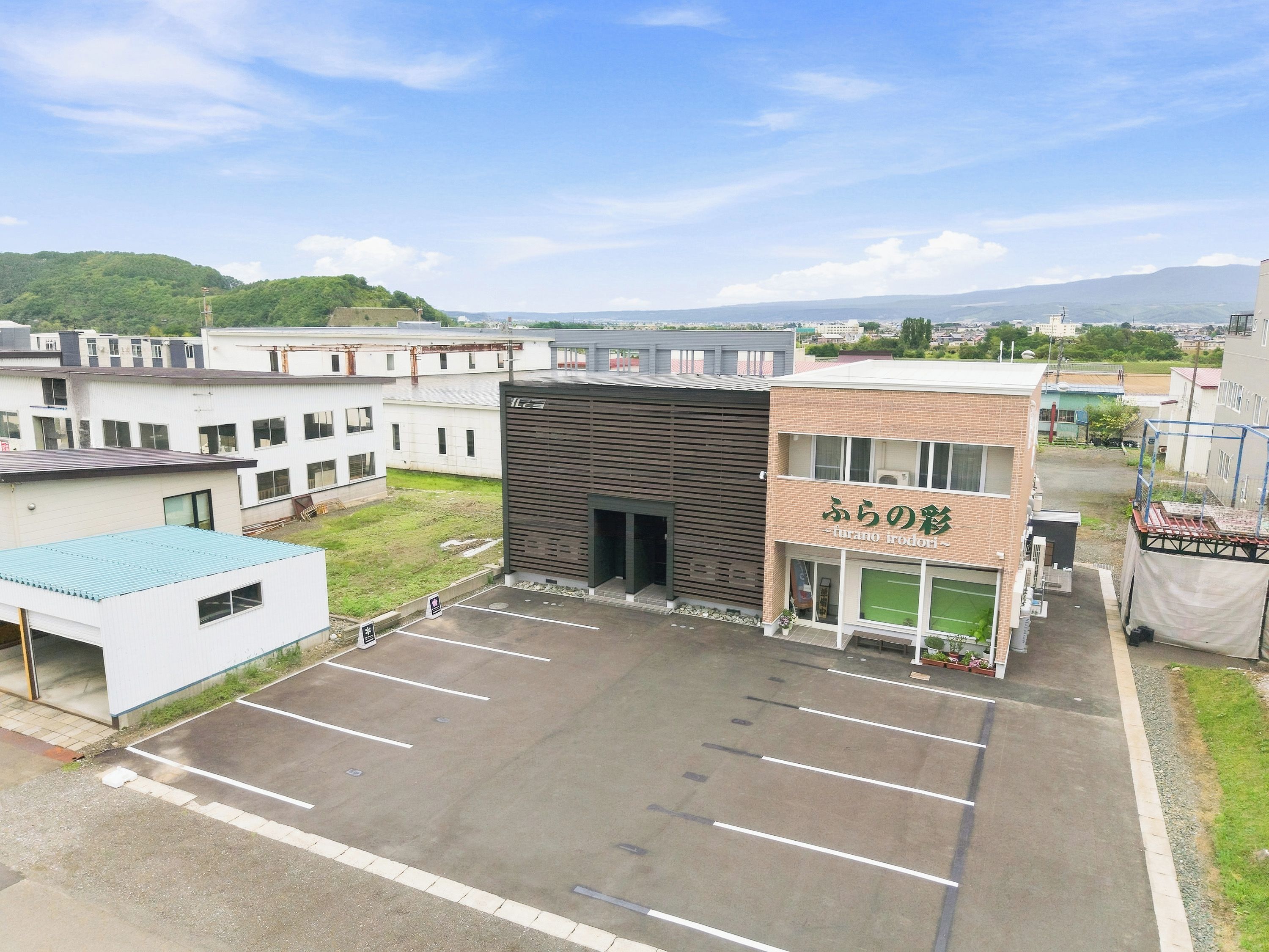 Un estacionamiento con un edificio que tiene un letrero con caracteres japoneses.