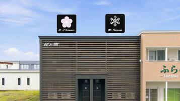 A building with a modern facade, a visible entrance, and a sign with Japanese characters.