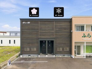 A building with a modern facade, a visible entrance, and a sign with Japanese characters. - Snow (Furano)