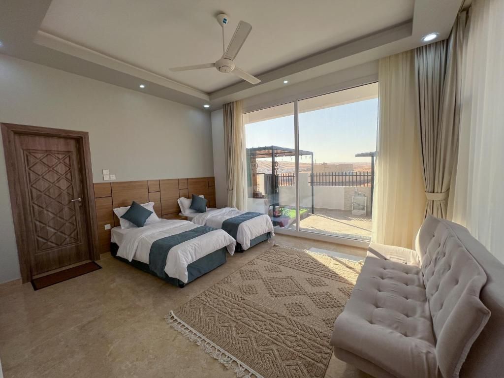 Ein Hotelzimmer mit zwei Betten, einer Couch, einem Deckenventilator und einem großen Fenster mit Blick.