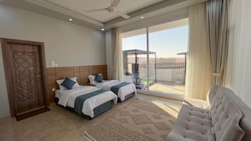 Ein Hotelzimmer mit zwei Betten, einer Couch, einem Deckenventilator und einem großen Fenster mit Blick.