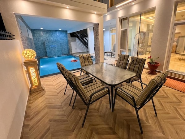 A dining area with a pool view, a staircase, and a glass door leading to a balcony.