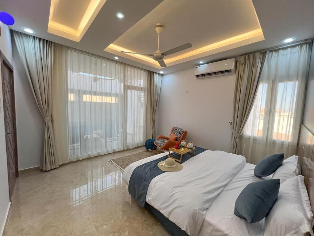 A modern bedroom with a large bed, a ceiling fan, and an air conditioning unit.