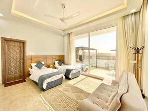 Une chambre d’hôtel avec deux lits, un canapé, un ventilateur de plafond et une vue sur l’extérieur.
