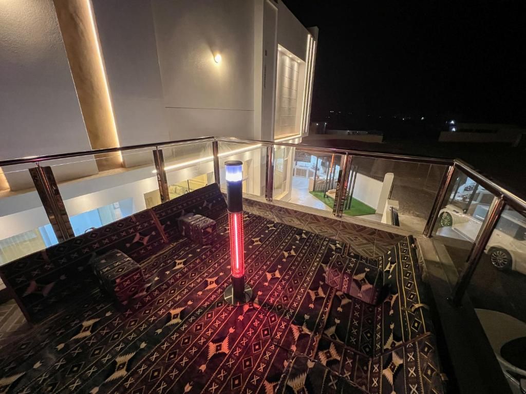 Ein Balkon mit einem gemusterten Boden, einem Glasgeländer und Blick auf ein Gebäude und eine Straße bei Nacht.