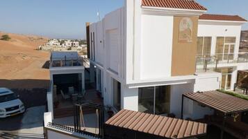 A modern two-story building with a flat roof, large windows, and a balcony.